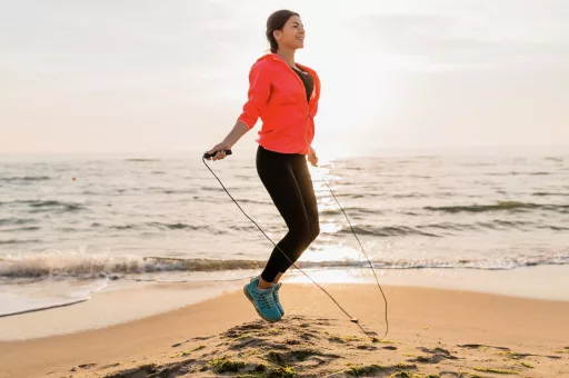 Femme s'exerçant à la corde à sauter sur la plage.