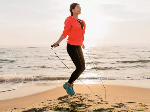 Femme s'exerçant à la corde à sauter sur la plage.