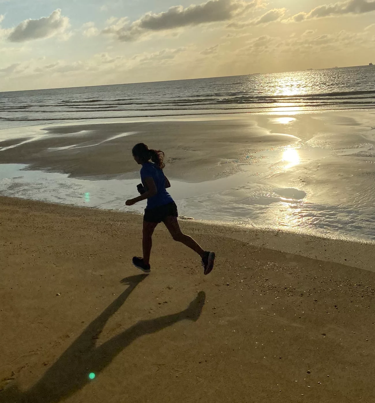 Femme courant sur plage au coucher du soleil.