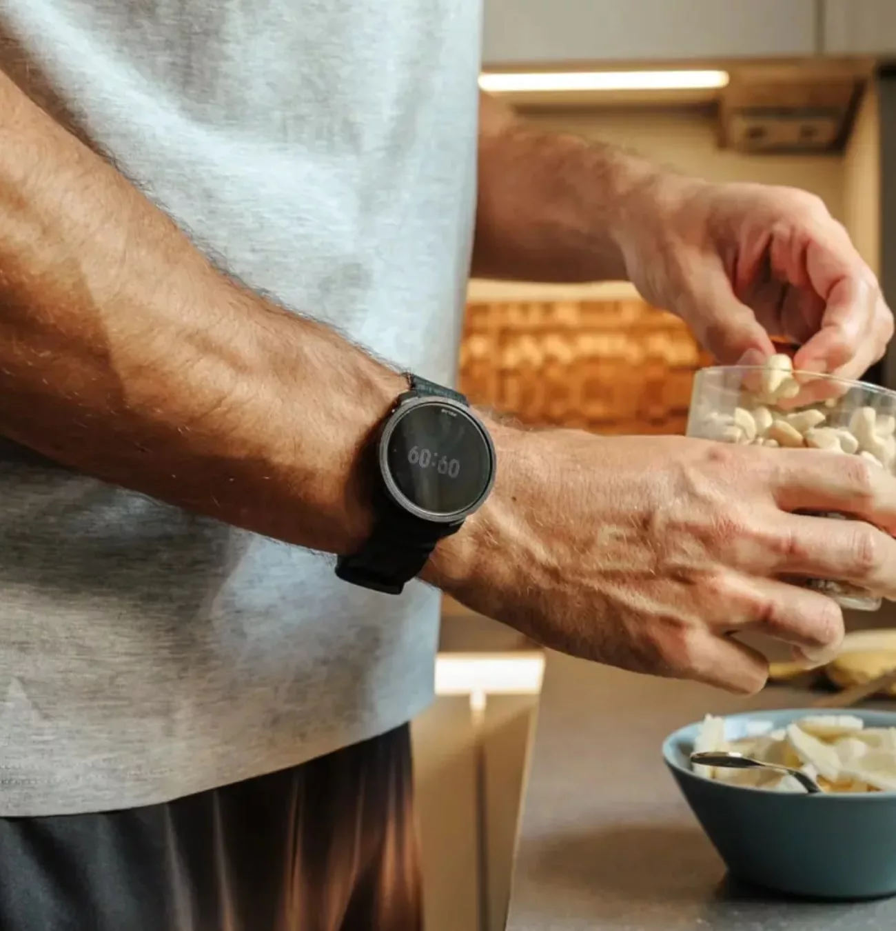 Homme avec montre prépare des noix en cuisine.