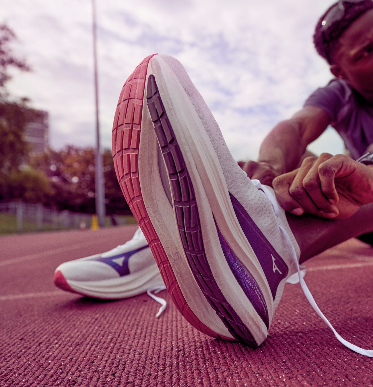 Coureur nouant ses chaussures sur piste d'athlétisme.