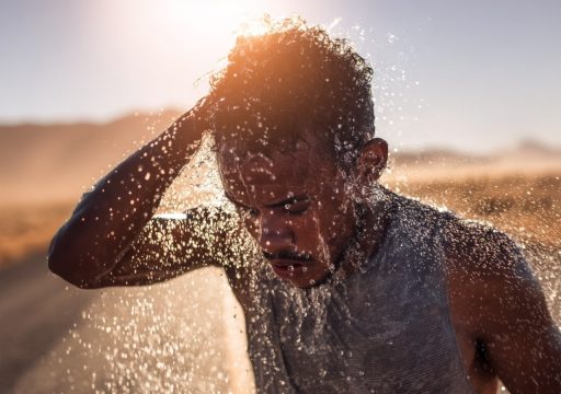 Homme se rafraîchissant avec de l'eau au soleil.