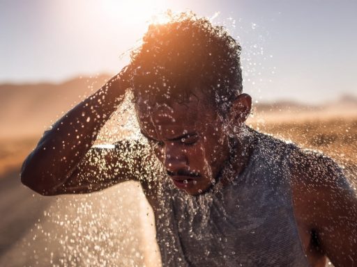 Homme se rafraîchissant avec de l'eau au soleil.