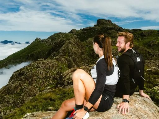 Couple assis sur rocher, vue montagneuse.