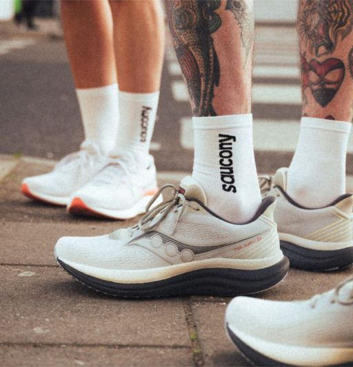 Baskets blanches Saucony sur trottoir urbain.