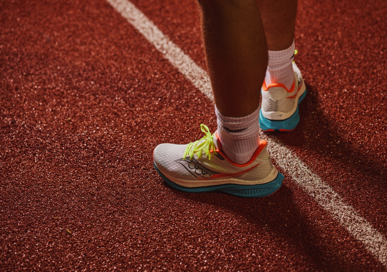 Coureur sur piste d'athlétisme en baskets colorées.