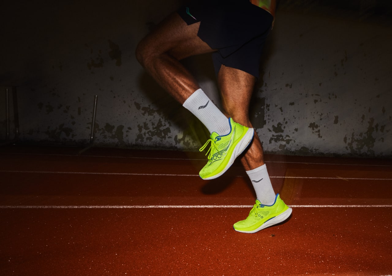 Coureur avec chaussures vertes sur piste intérieure.