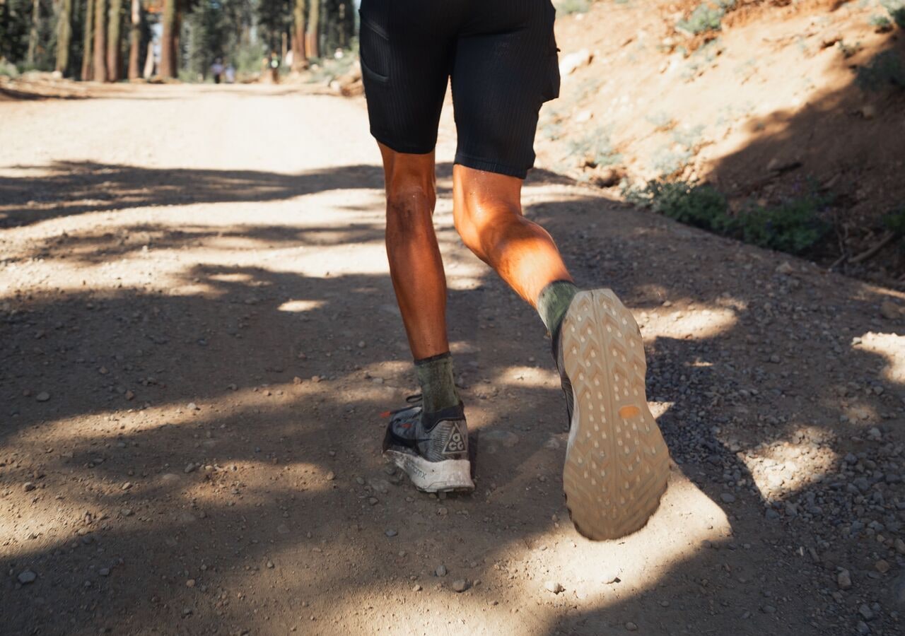 Personne courant sur un chemin de terre forestier. nike acg ultrafly