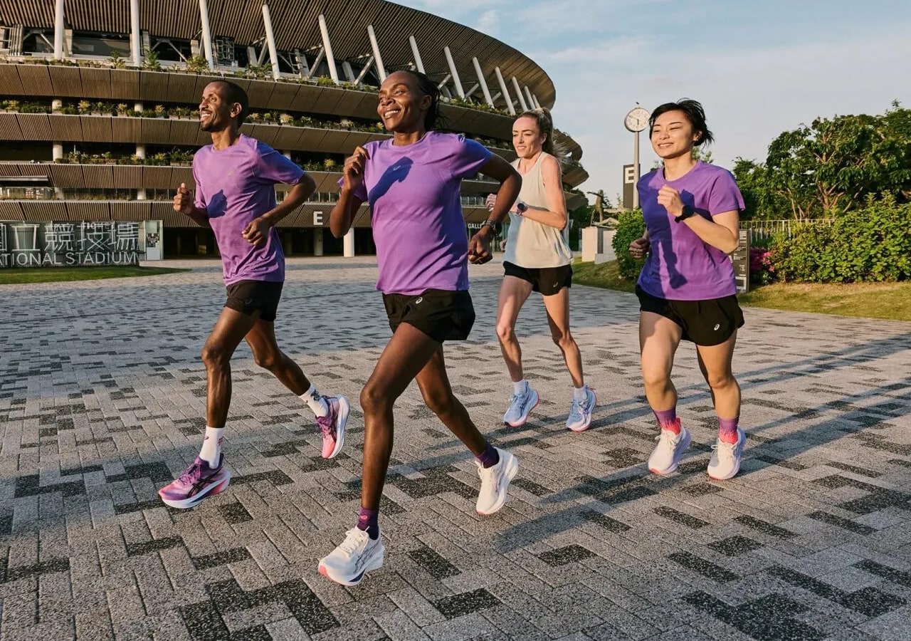Groupe de coureurs souriants près d'un stade.