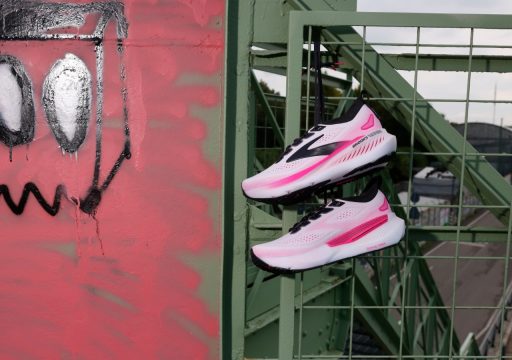 brooks glycerin gts 23 Chaussures roses suspendues sur grille verte, graffiti rouge.