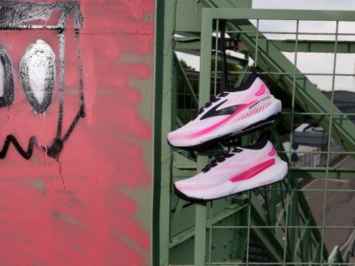 brooks glycerin gts 23 Chaussures roses suspendues sur grille verte, graffiti rouge.