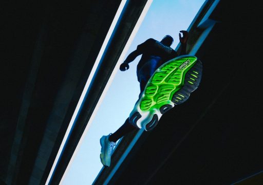 Coureur avec des chaussures verte sous un pont.