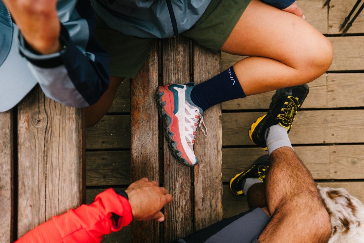 Randonneurs assis sur banc en bois, chaussures visibles