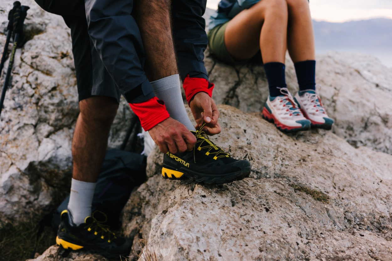 Randonneurs attachant leurs chaussures sur rocher montagneux