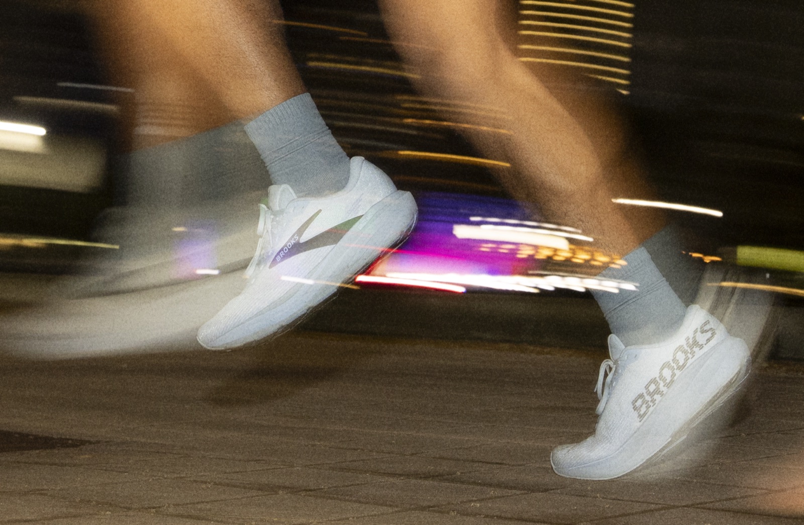 Gros plan sur l’avant-pied de deux Brooks Ghost Amp en pleine foulée de nuit