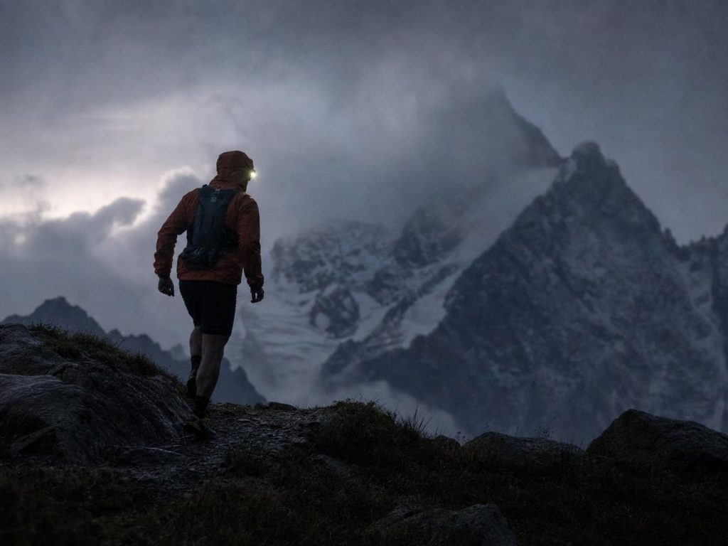 Randonneur avec lampe frontale face aux montagnes brumeuses